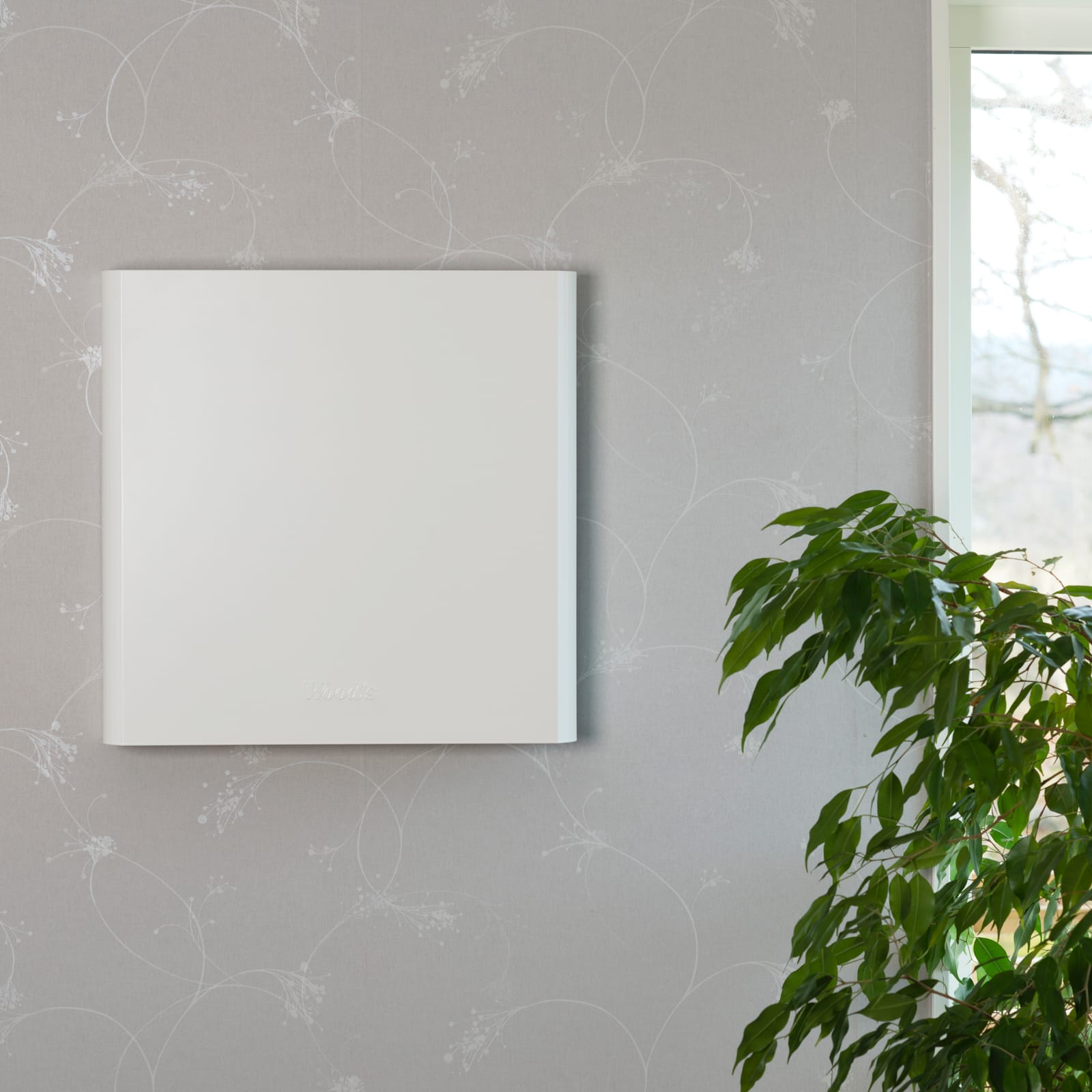 Wood's TALL 155 luchtreiniger aan een lichte wand naast een kamerplant
